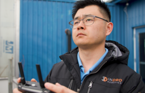 Kaiwen Xu holding a drone controller and looking up into the sky