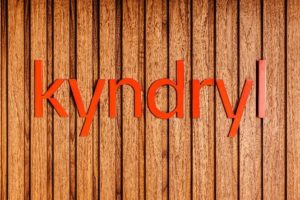 Kyndryl's red logo featuring the company name in red font, is displayed on a wall of vertical wood panels.