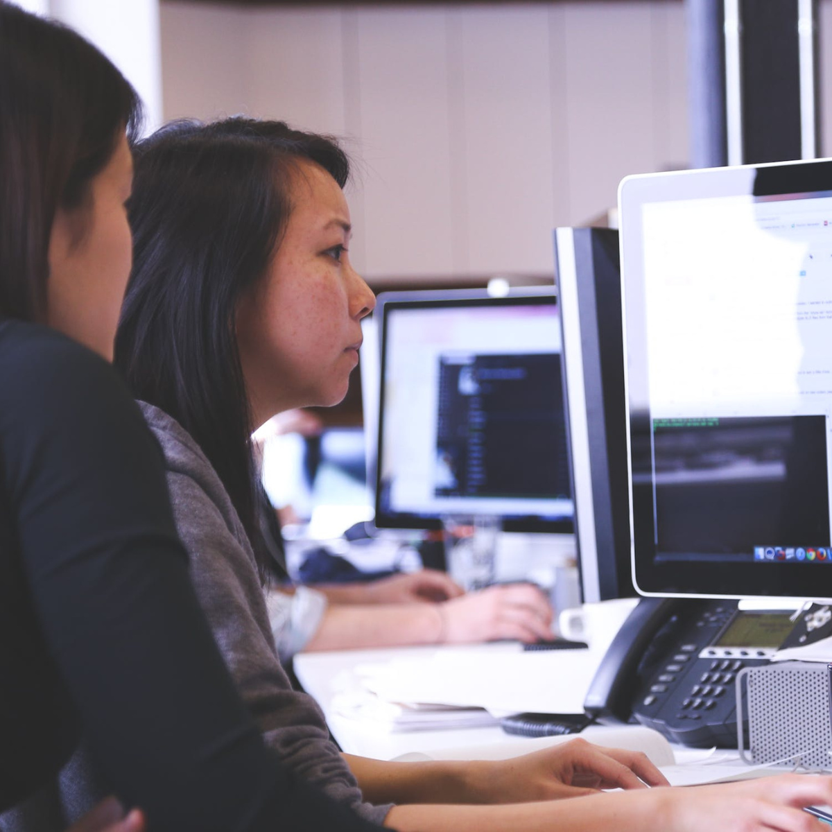 Two Women Sitting in Front of Computer Monitor