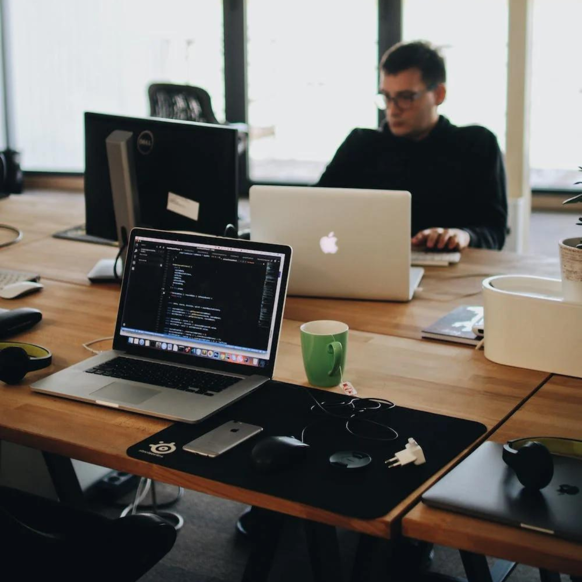 Man in Black Shirt Sits Behind Desk With Computers