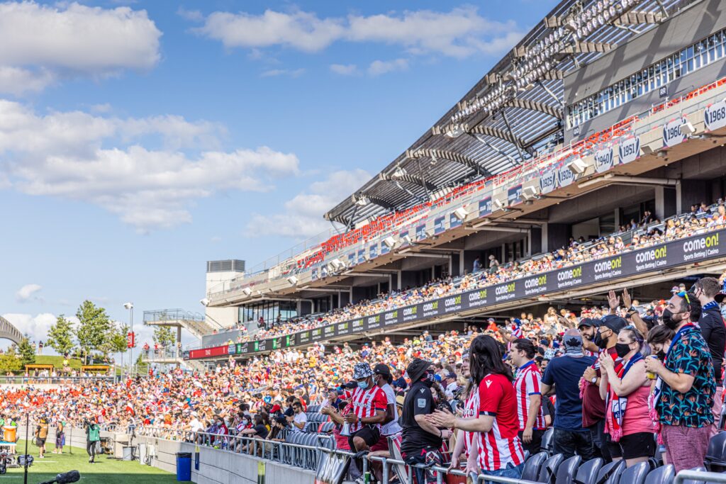 Atlético Ottawa's fans celebrating in the stands at TD place on a slightly cloudy day.