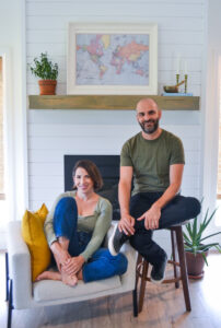 Sarah and Ryan Gencarelli, owners of wild idea co. seated and smiling in a living room setting.