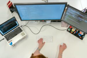 An overhead view of a programmer working with code across multiple screens