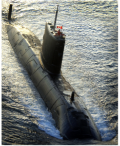 An overhead view of a submarine moving on top of the water in the direction of the camera. 