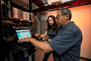 Two people collaborating at a monitor, overlooking data on site. 