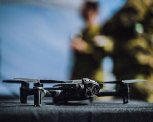 An image of a drone in the foreground, with the operators out of focus in the background. 