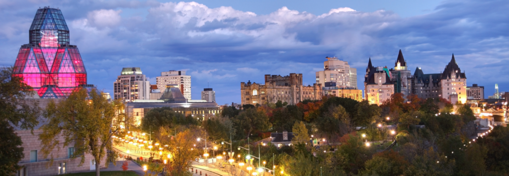 An image of the Ottawa skyline at dusk, overlooking the Pariliament buildings and the National Arts Centre
