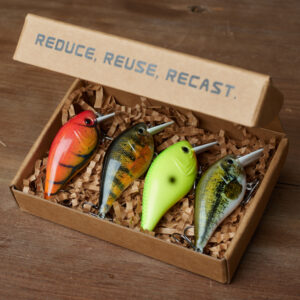 Four fishing lures are arranged in a presentation box - with the words reduce, reuse recast written above it. 