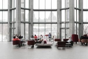 A group gathers to work in a casual, open space with a variety of seating options in front of a large window display. 