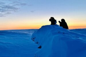 Two people conduct research in a snowy climate.
