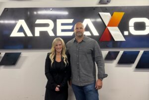 Invest Ottawa President and CEO Sonya Shorey stands with Glenn R. Cowan - Founder and Managing Director, ONE9 in front of a sign for Area X.O.