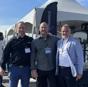 Three people smile for a photo at an outdoor event. 