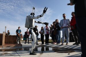 A humanoid robot appears to be dancing for a group gathered to watch at an outdoor event. 