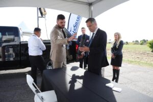 Mayor Mark Sutcliffe examines what appears to be a small rocket, under the guidance of another person appearing to be explaining the technology behind it. 
