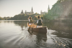 A duo canoes on calm waters past Parliament Hill.