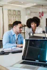 Two people engage in a collaborative discussion in front of a computer. 