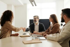 A handshake is made across the table at a business meeting. 