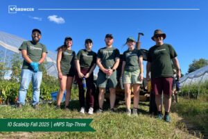 The team for Growcer stands outside in front of farming equipment on a sunny day. 
