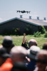 A person releases a drone outside as a crowd watches on.