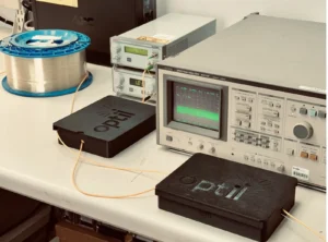 Components related to photonic RF testing are laid out on a desk.